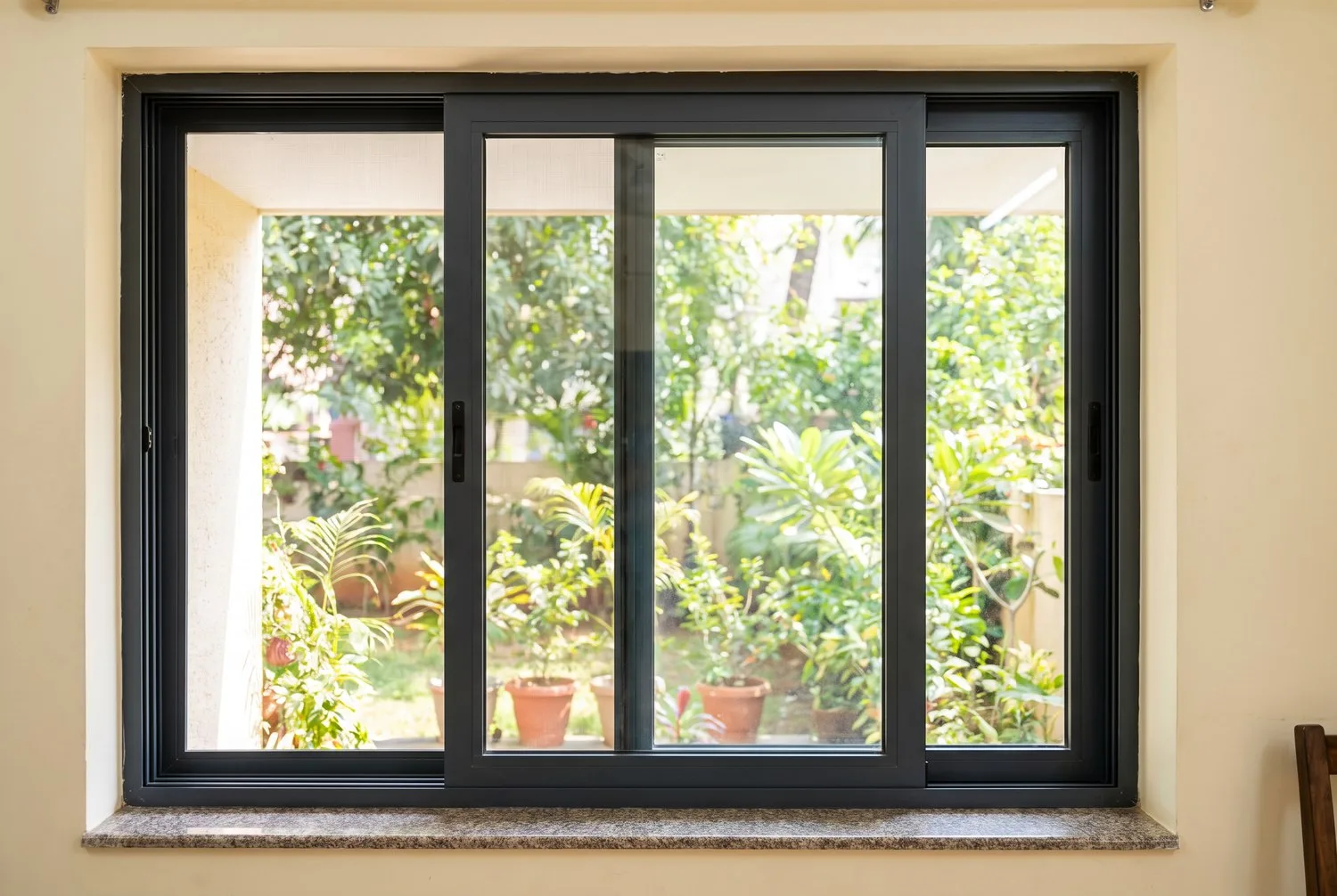 Two-track aluminium sliding window with mosquito mesh, set in a wall