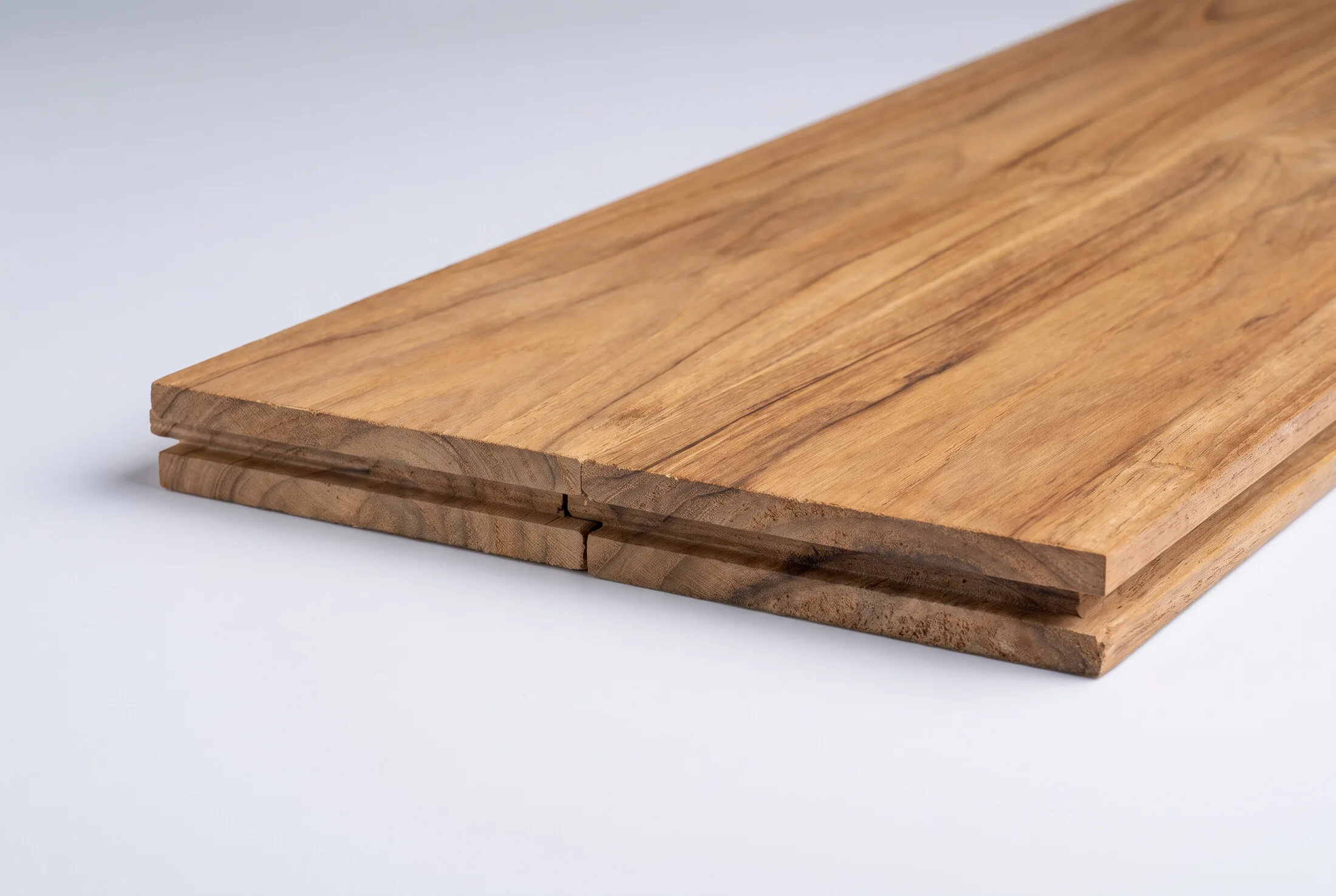 Solid teak flooring plank showing the milled tongue-and-groove edge
